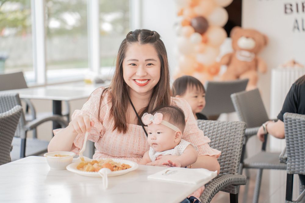 Family enjoying a casual meal together at a restaurant with orange balloons in the background.
