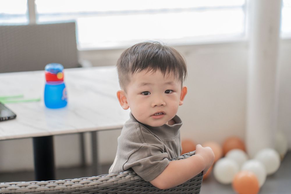 Young child sitting at table with toy in modern interior setting.