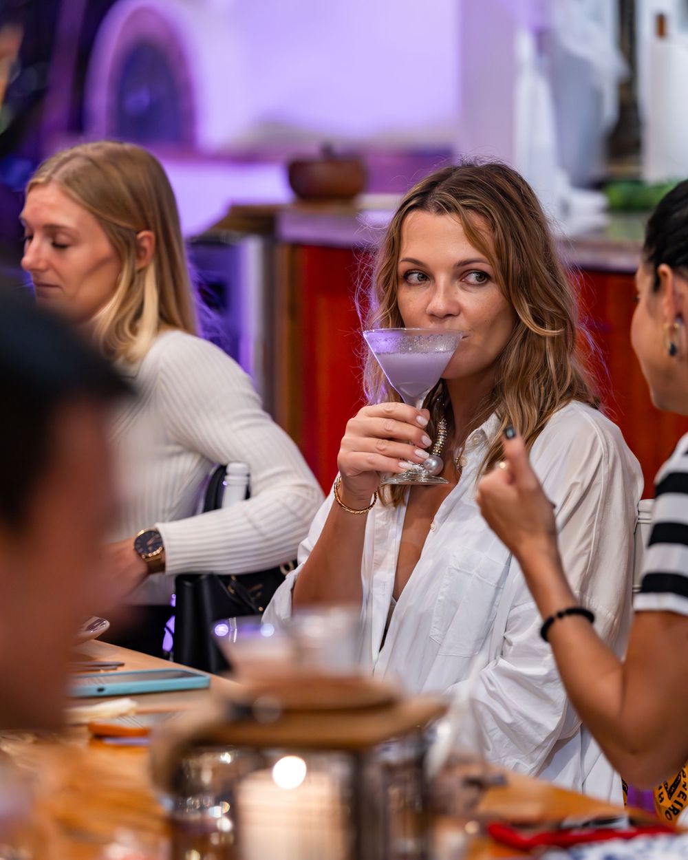Group enjoying colorful cocktails and conversation at an upscale bar.