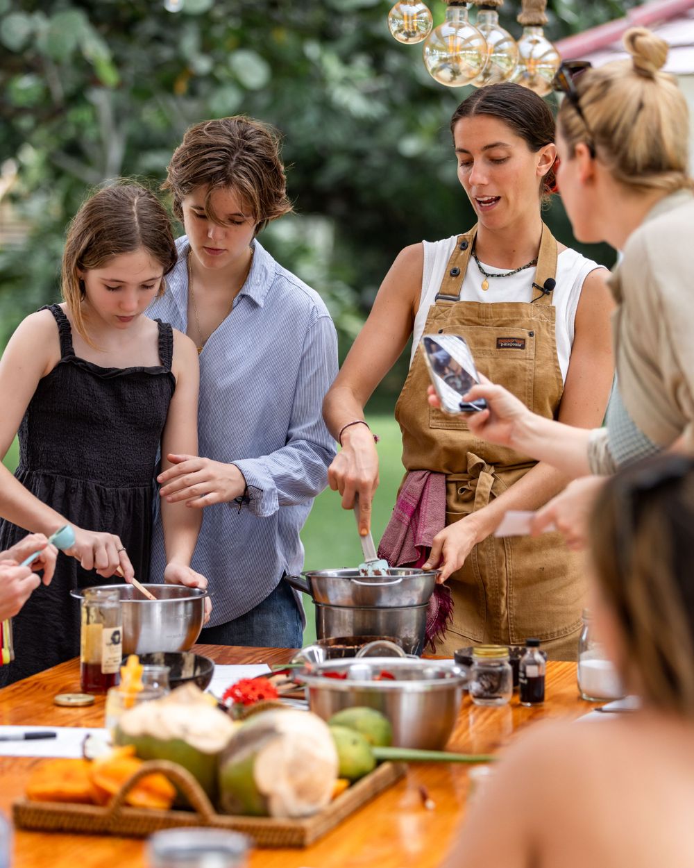 Cooking class participants gathered around a table preparing ingredients outdoors.