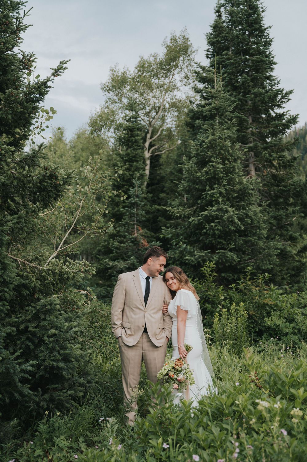 A bride and groom embrace while being photographed by their talented Utah natural light photographer.