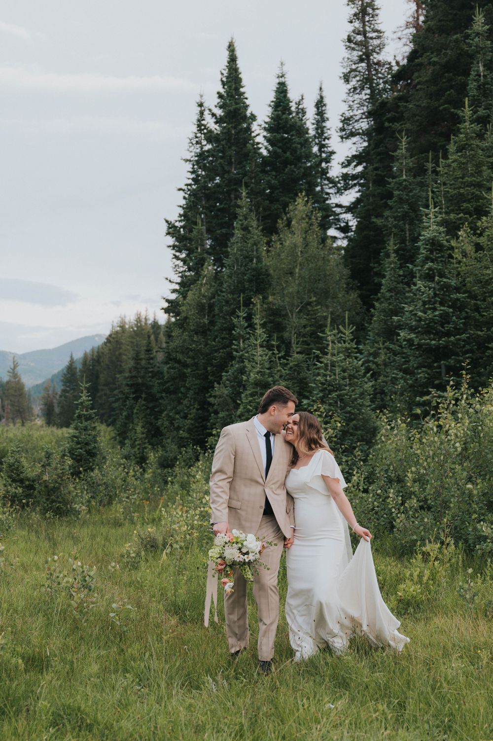 Bride and groom kiss in the pine tree-filled mountains of Salt Lake City, Utah. Captured by a Utah wedding photgrapher.