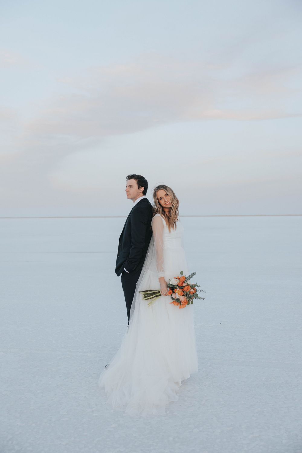 Bride smiles for the camera at the Utah Salt Flats while taking her bridals with her destination wedding photographer.