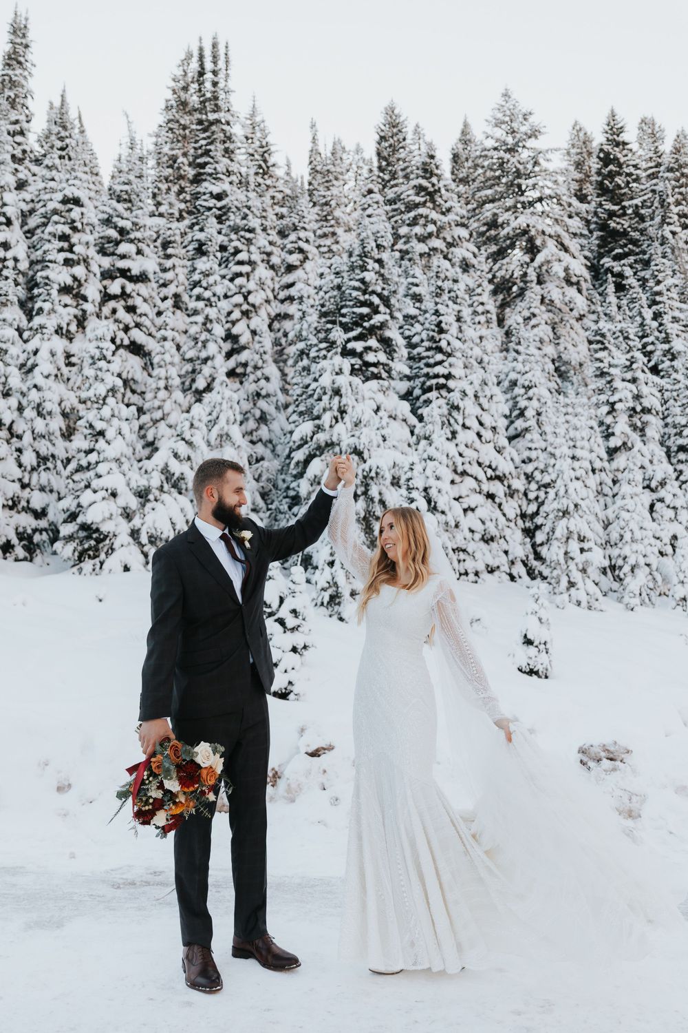 Bride and groom smile as they take their wedding portraits in the snowy mountains of Salt Lake City, Utah.