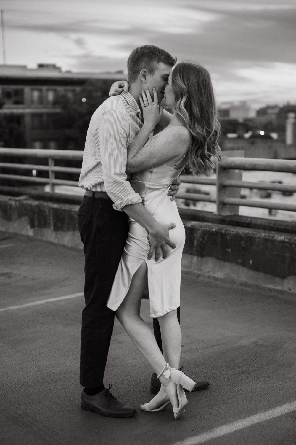 A black and white photo captures an intimate moment between a couple on a rooftop.