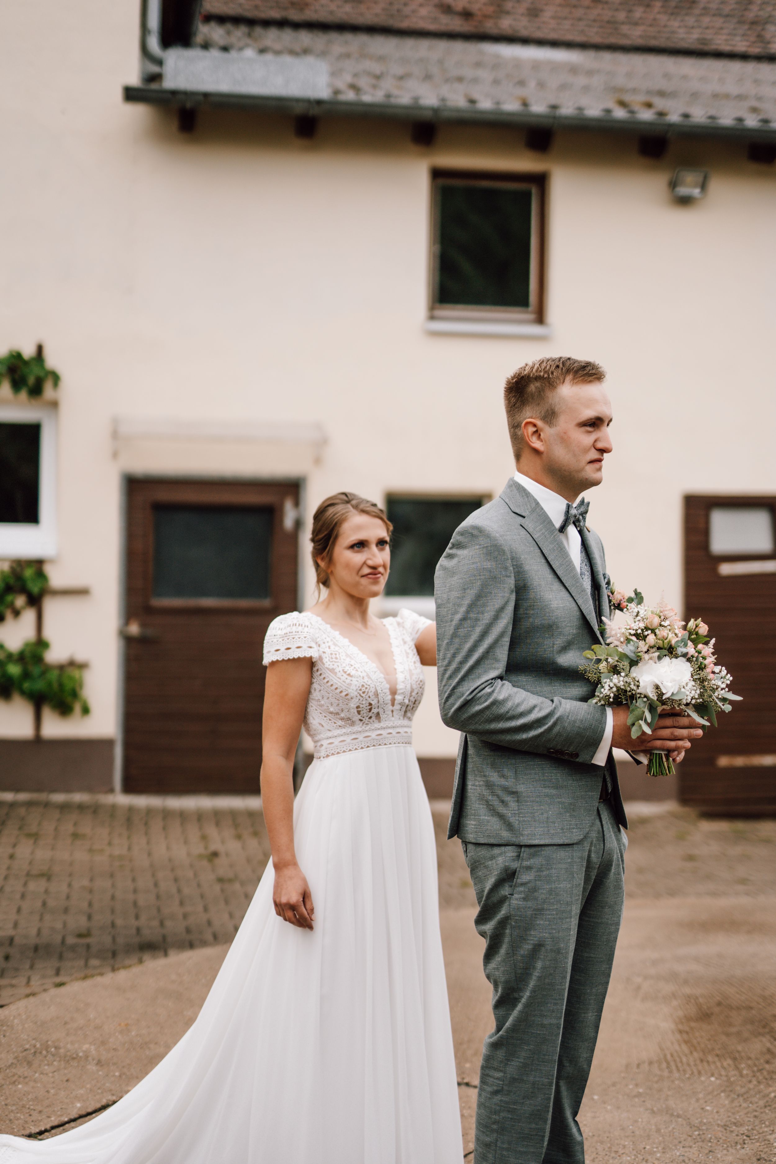 Wedding couple in elegant attire standing outdoors near building.