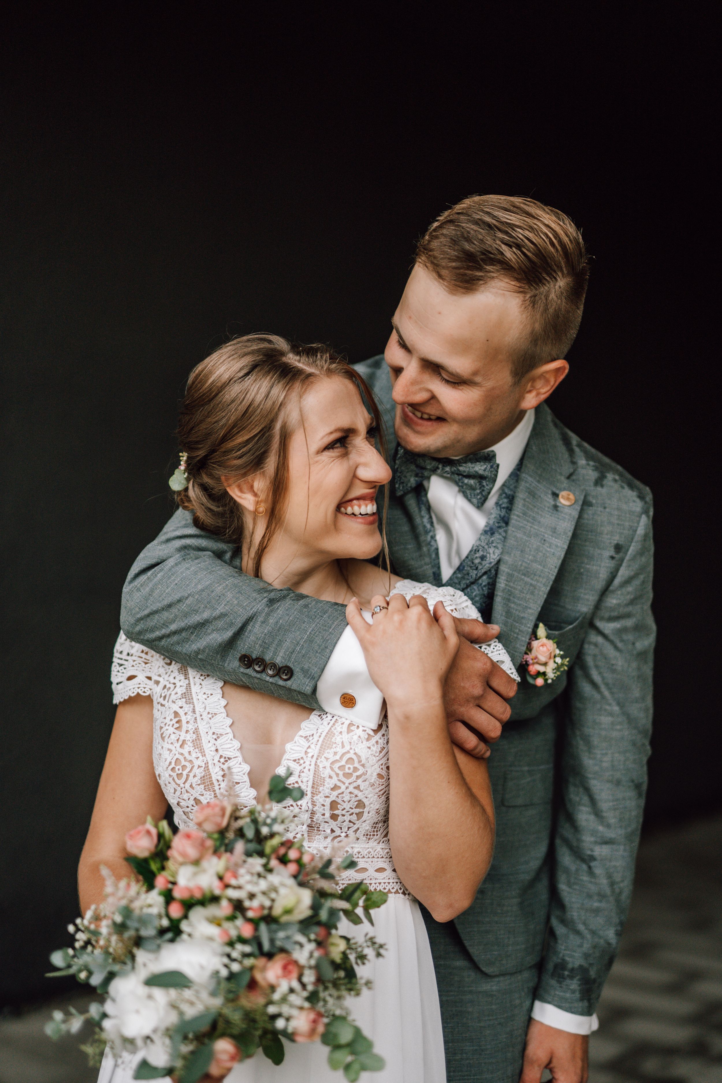 Candid wedding moment showing natural smiles and floral bouquet details.