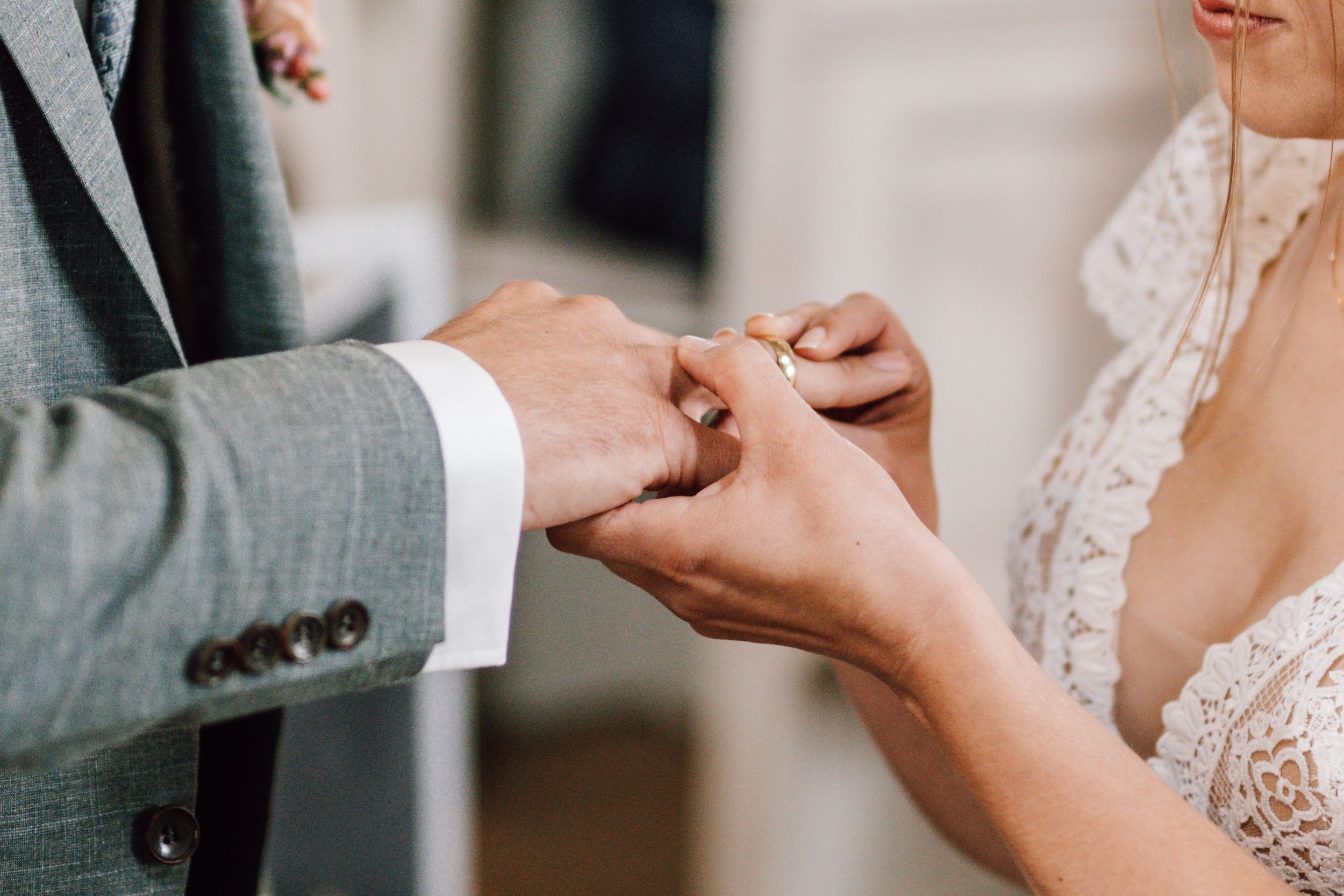 Close-up of hands exchanging rings during wedding ceremony.