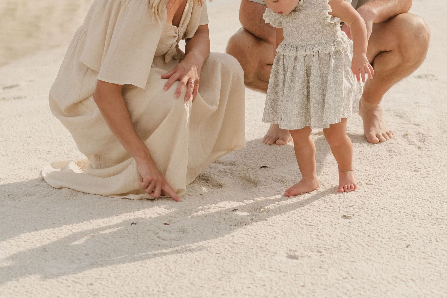 Close-up of bare feet walking on sandy beach with flowing white fabric.