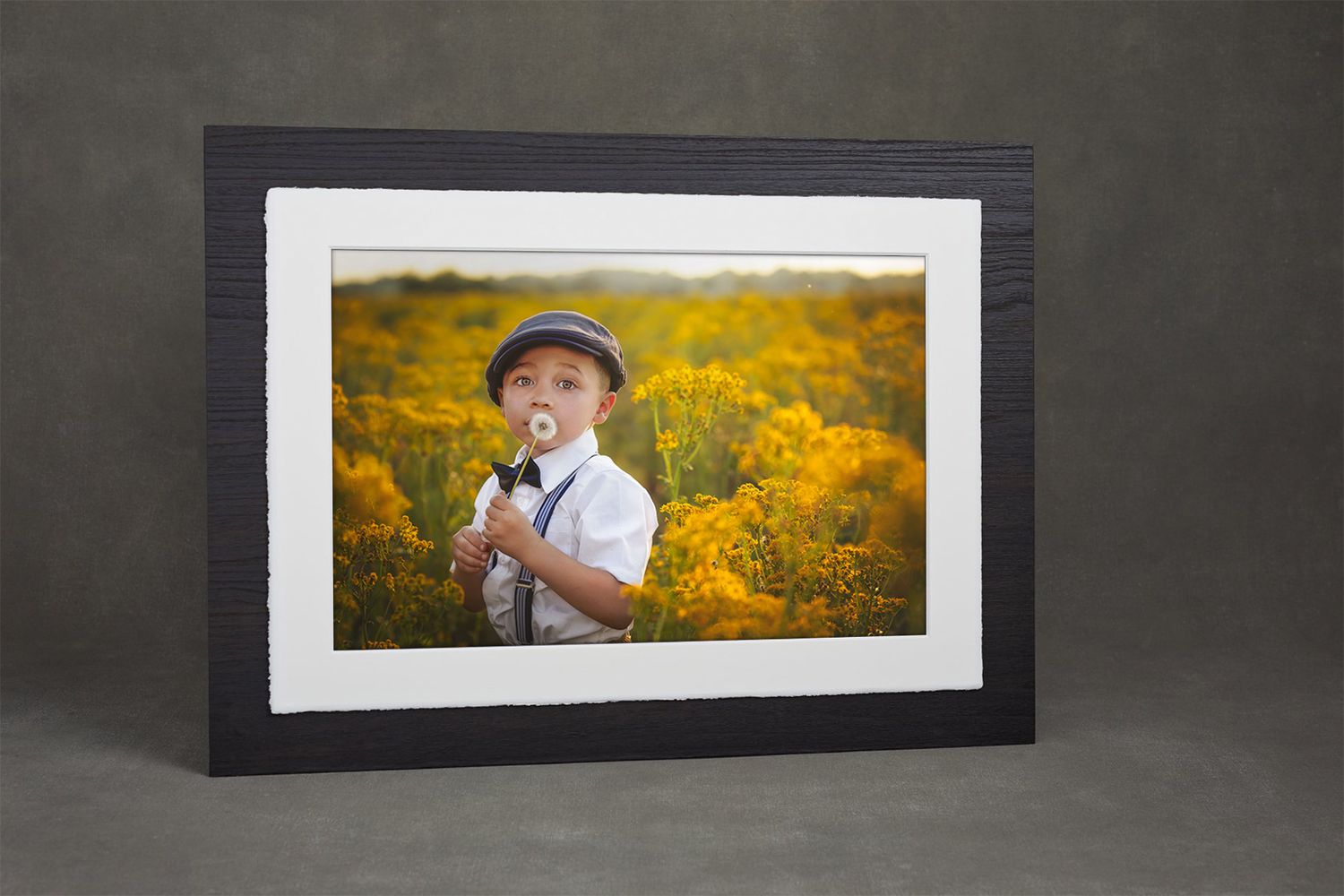 A framed photo shows a child in white clothing standing among bright yellow wildflowers.