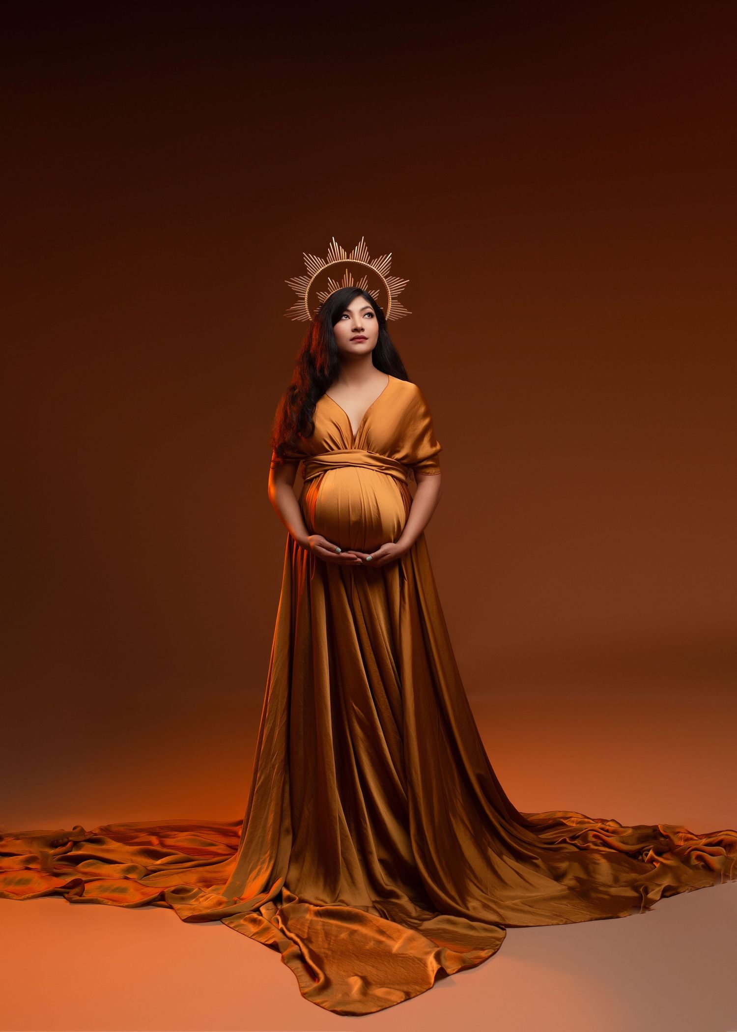 an expecting mother looking like a goddess poses for maternity photos with her hands supporting her belly