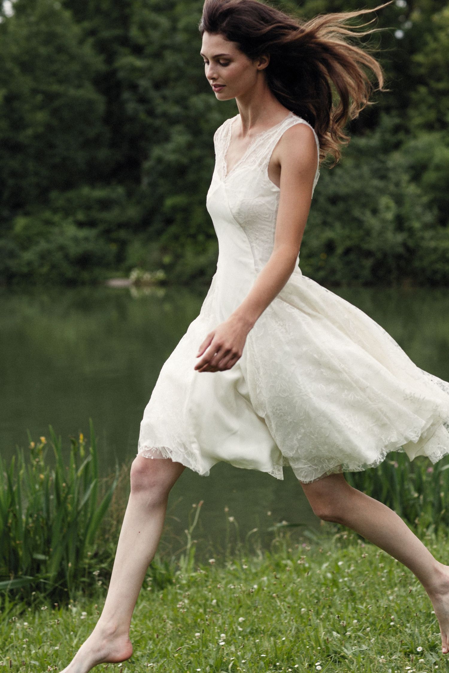 Whimsical wedding dress flowing in motion as model runs through summer meadow.