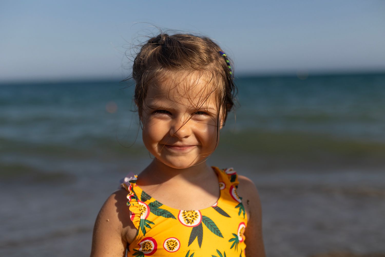 With summer yellow swimming suit the beautiful girl is looking at the camera.
