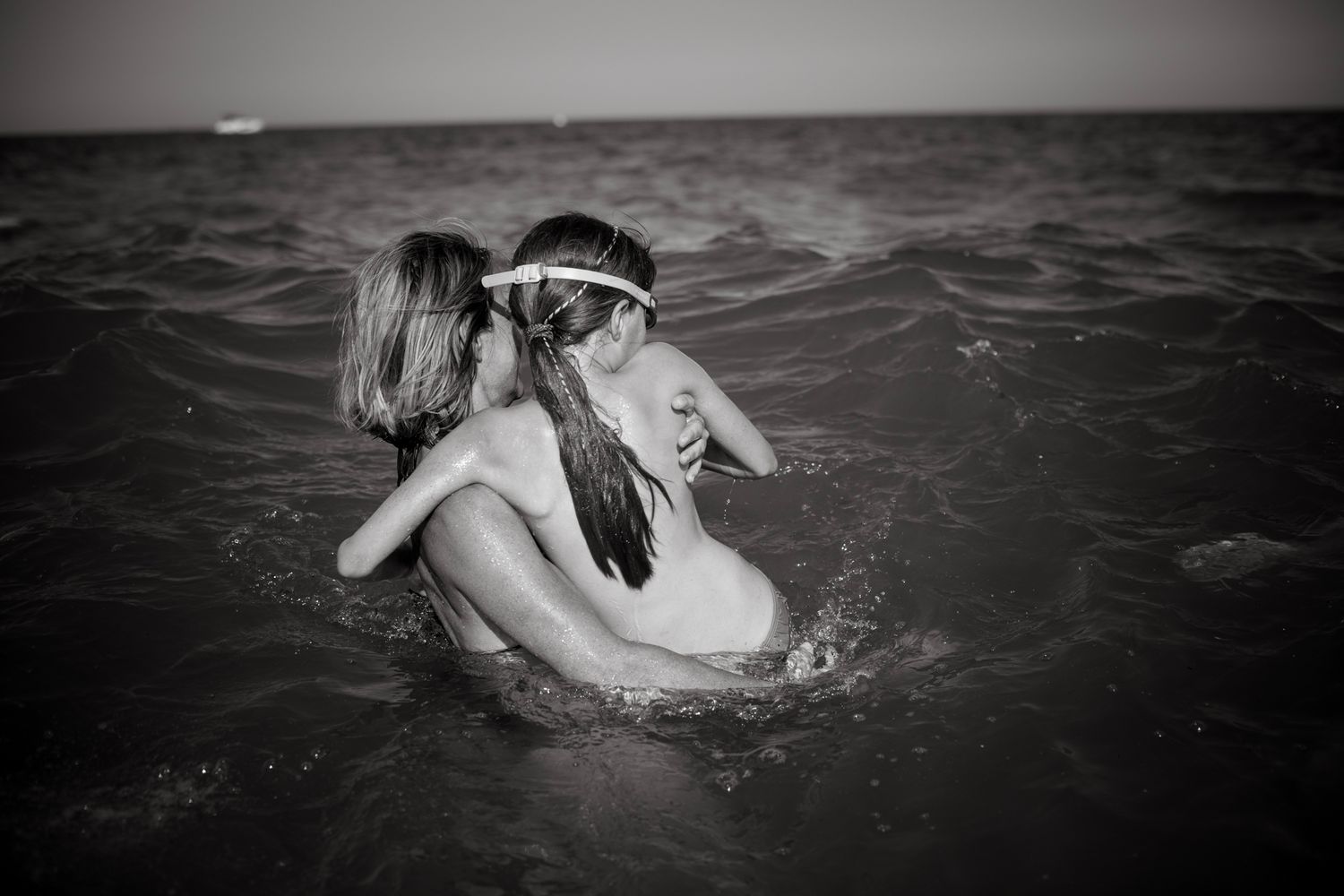 Girl enter the sea on her mother hands.