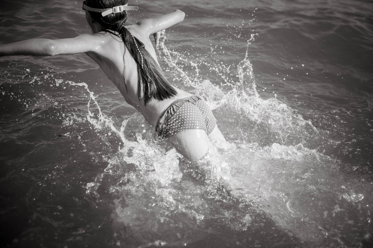 Girl jumps into the water with her googles.