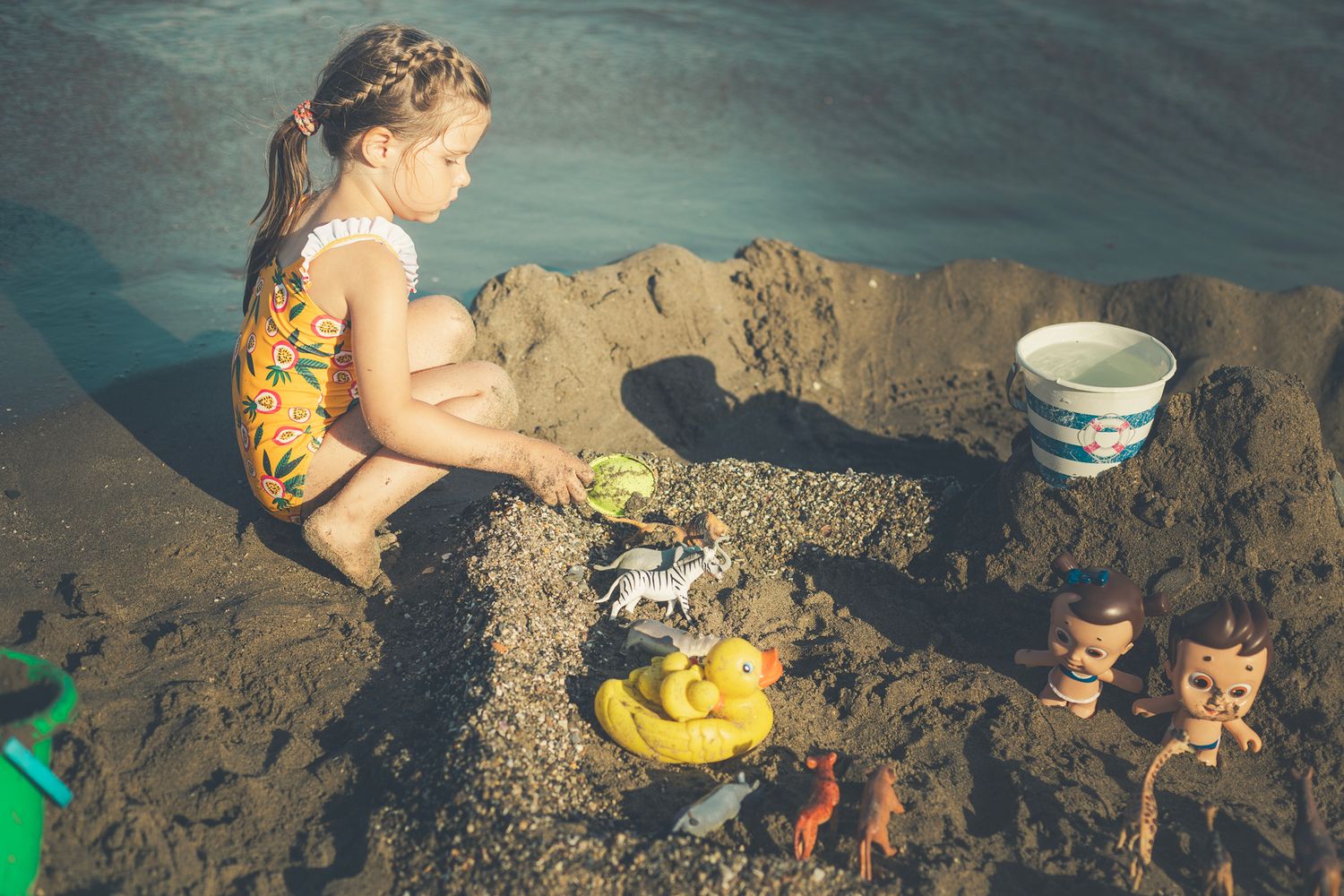 Girl sitting in the sand surrounding with all her toys at malaga beach.