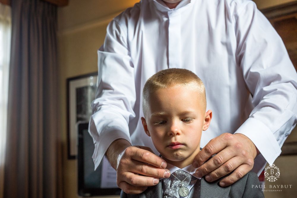 A close-up shot of hands adjusting a young boy's formal attire.