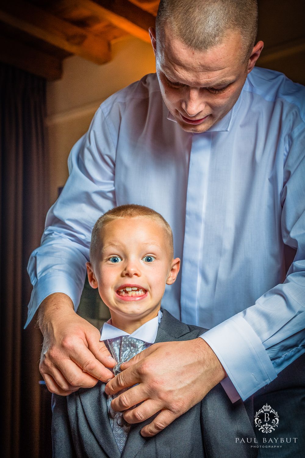 A touching moment captured as a man helps a young boy with his formal attire.