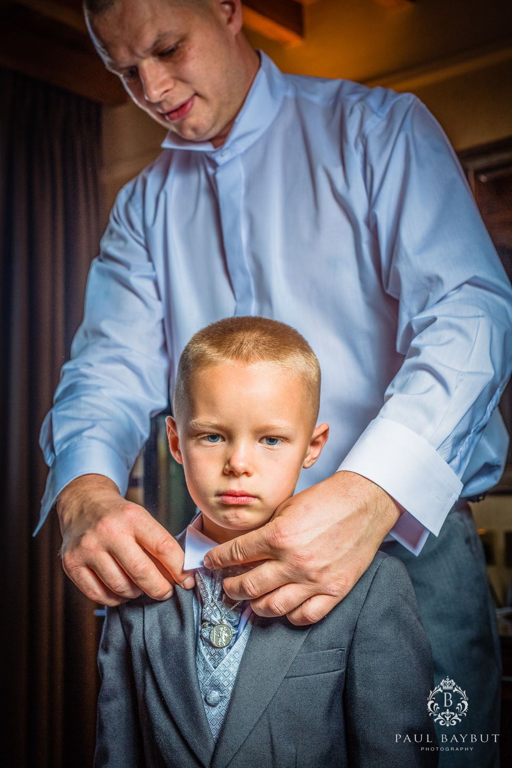 An intimate moment showing a man helping a young boy prepare in formal wear.