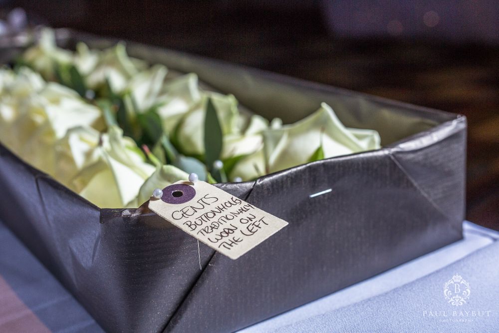 Close-up of delicate desserts arranged in a black box with a small tag attached.