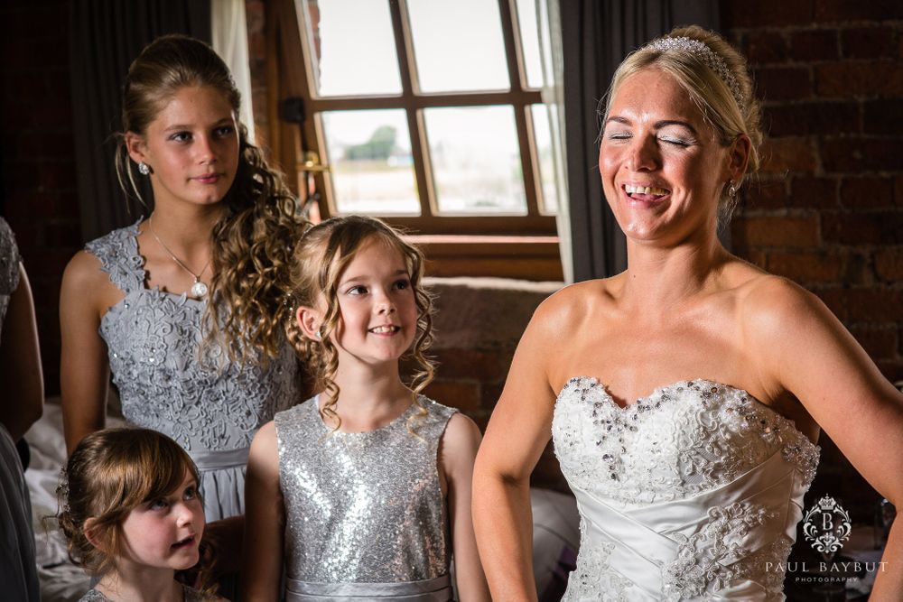 Joyful wedding party gathering in a room with exposed brick and natural window light.
