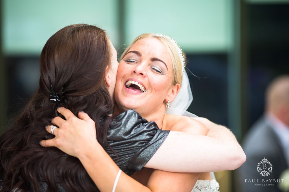 Two people share a joyful embrace and laughter at a wedding celebration.