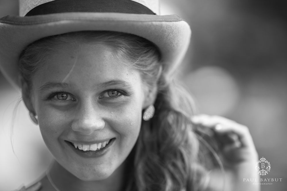 A black and white portrait shows someone in a hat with a bright, genuine smile.