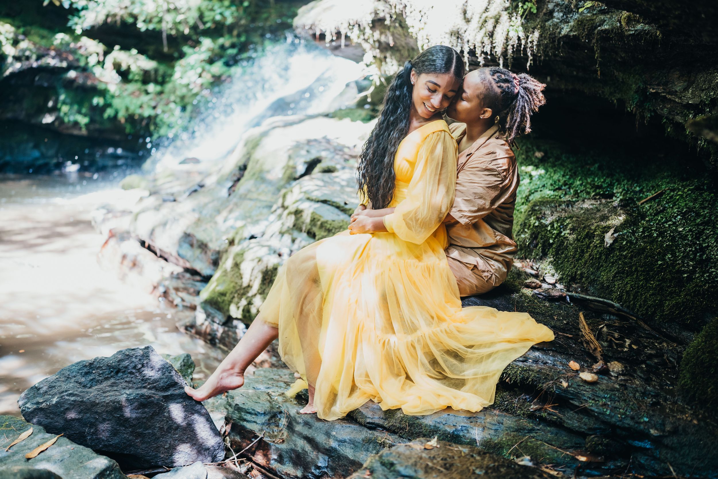 Lesbian couple poses for an engagement photoshoot at a North Georgia waterfall near Clayton