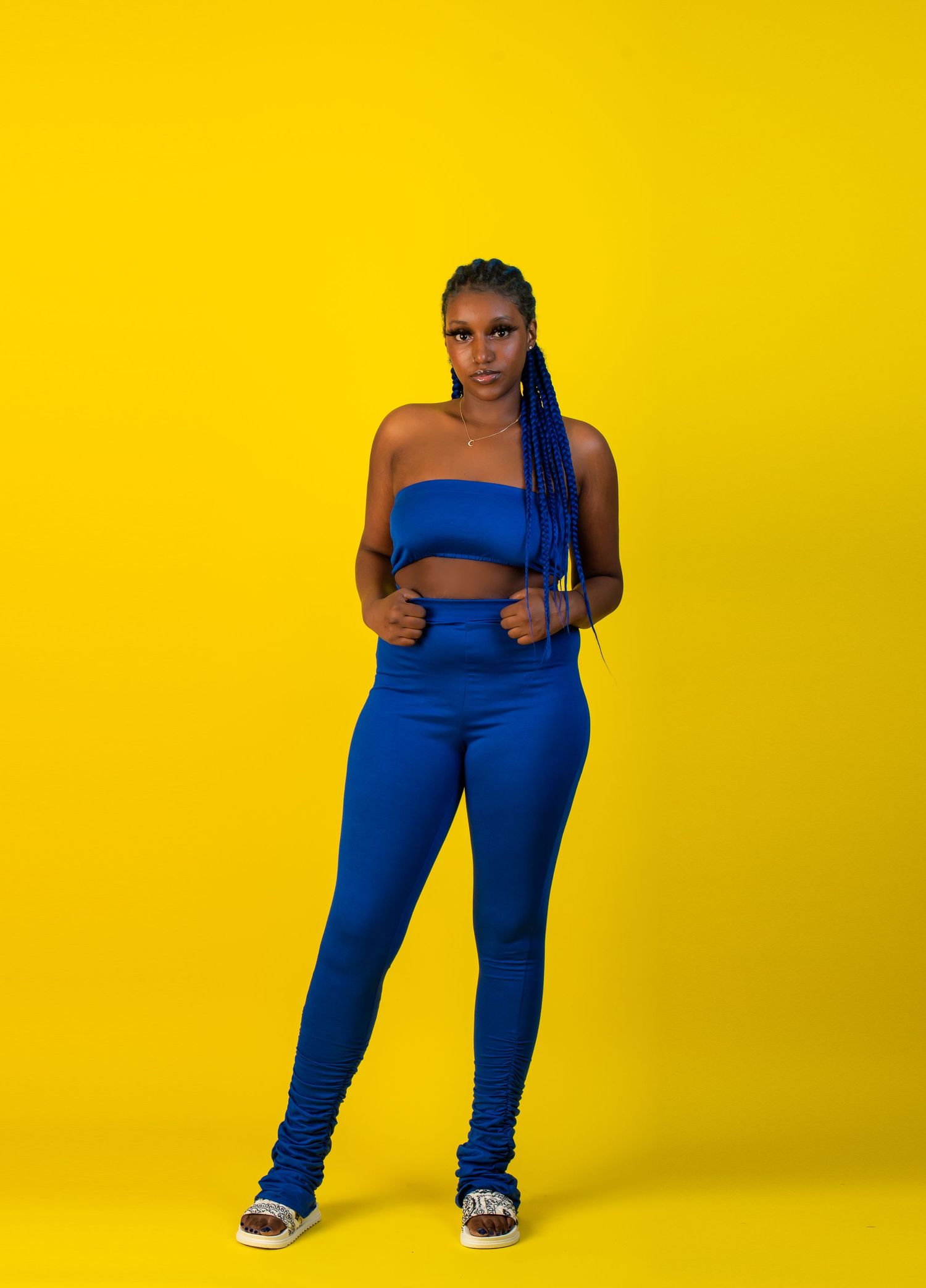 Fashion poses against yellow backdrop wearing bright blue athletic wear.