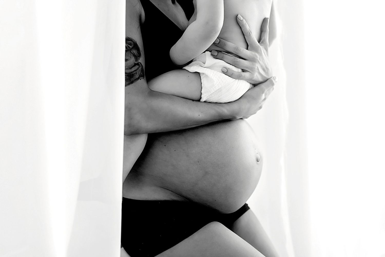 Artistic black and white maternity photo showing pregnant belly.