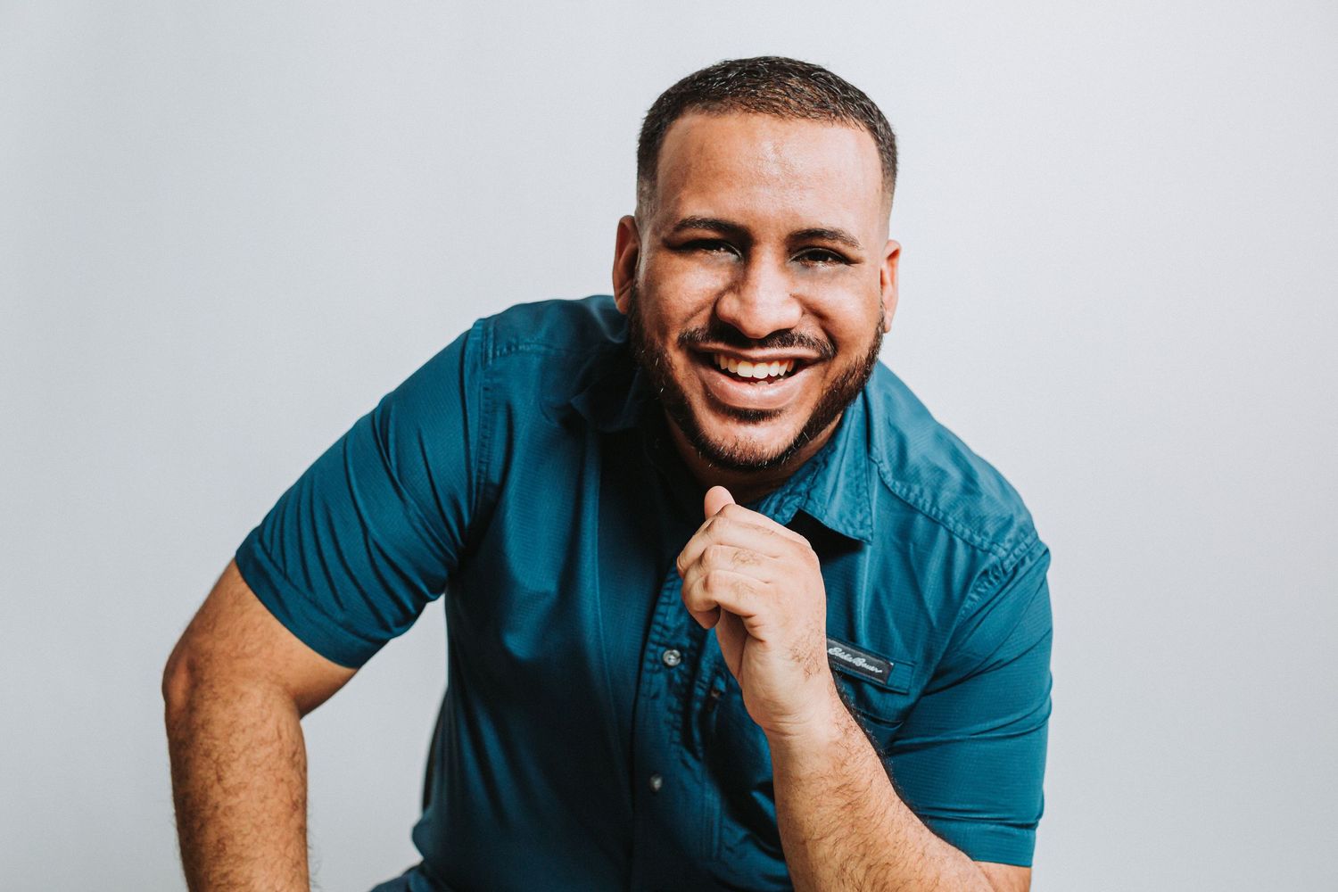 Portrait of a bearded man wearing a teal polo shirt smiling warmly at the camera.