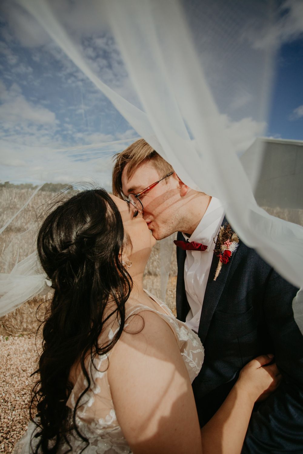 brunette bride kissing husband under their veil at Redwing Farm