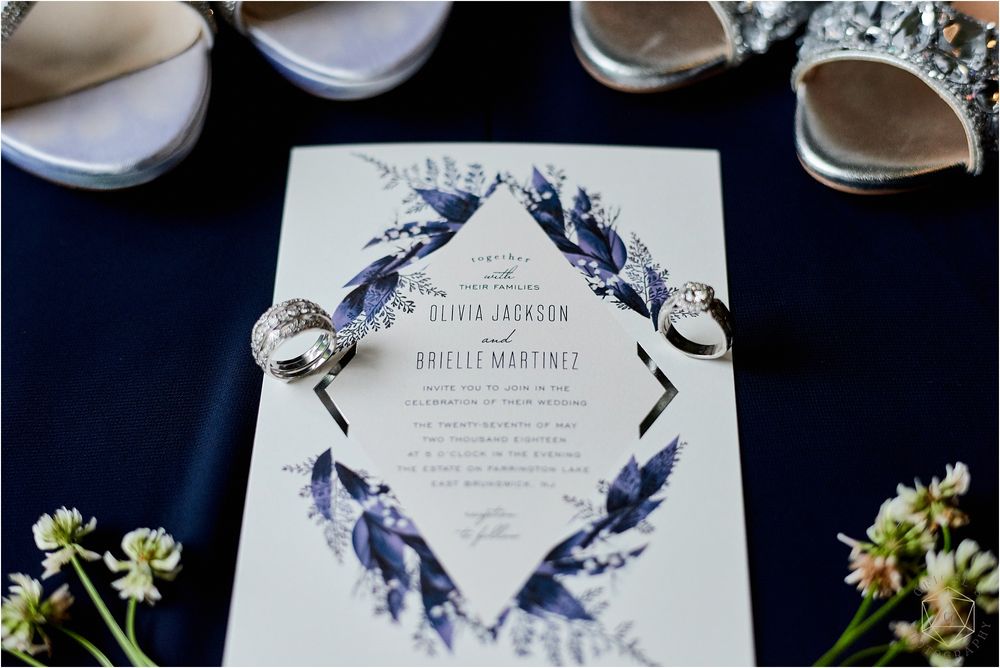 Wedding rings and invitation featuring blue feather design with floral accents.