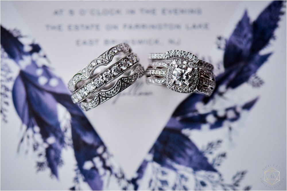 Detailed shot of vintage-style wedding rings on invitation with blue feather motif.