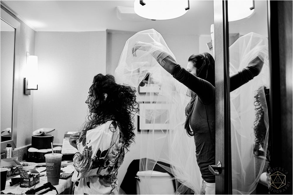 Black and white photo of wedding preparation with flowing veil movement.