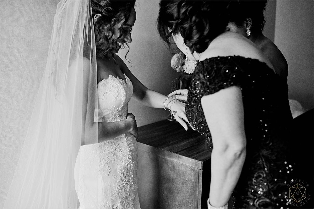 Black and white photo showing final wedding dress adjustments being made.