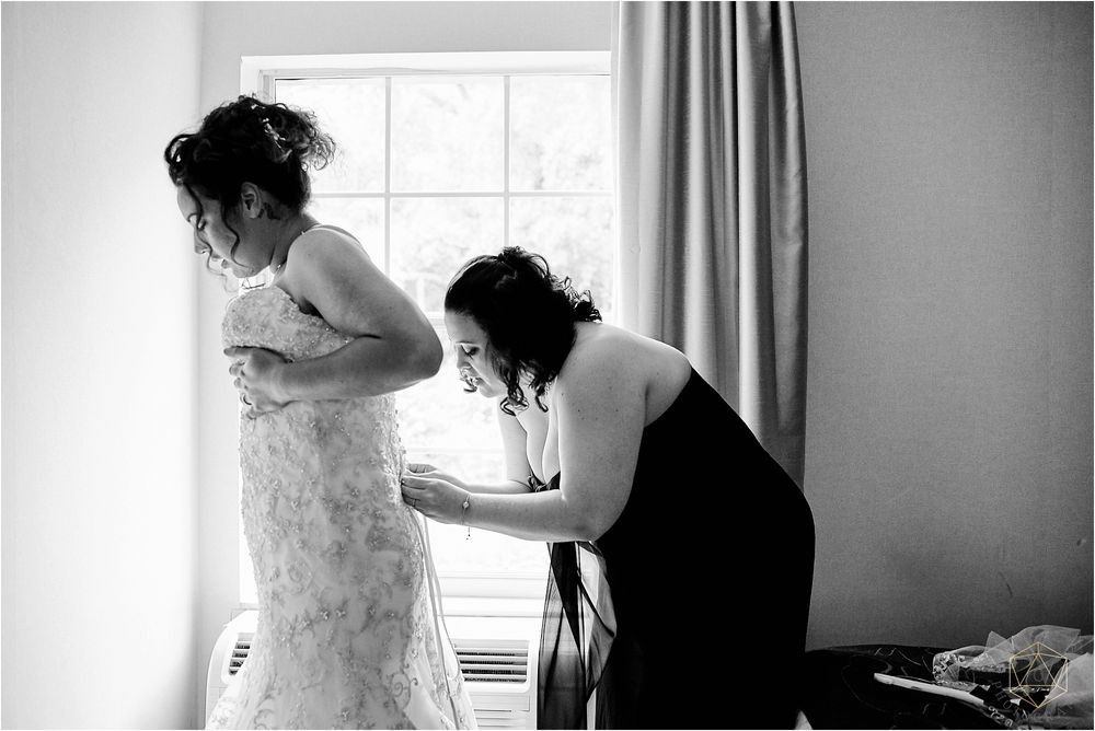 Woman in dark blue formal dress smiling during wedding preparations.