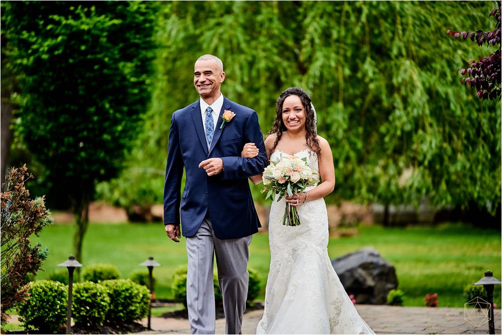 A couple walks arm in arm down a garden path during their wedding ceremony.