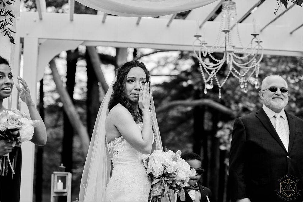 Black and white photo of a bride having an emotional moment during her outdoor wedding ceremony.