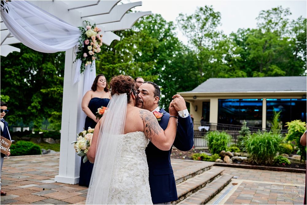 Wedding guests embrace and celebrate during an outdoor garden reception.