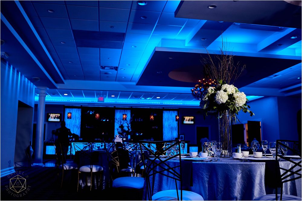 Wedding reception venue with dramatic blue lighting and elegant table settings.