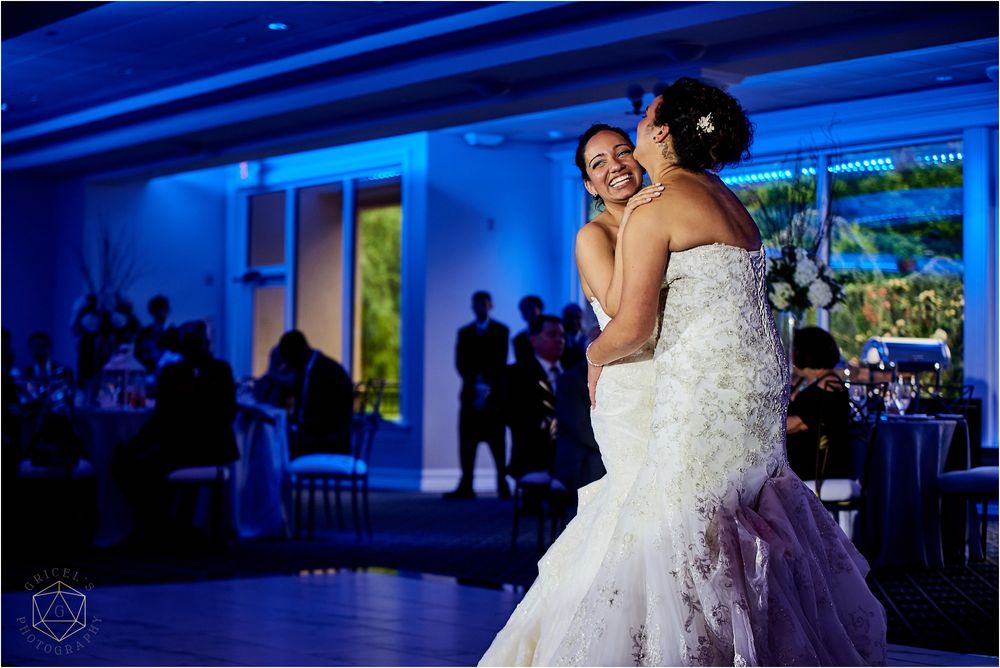 A couple shares an intimate dance moment at their wedding reception under dramatic blue lighting.