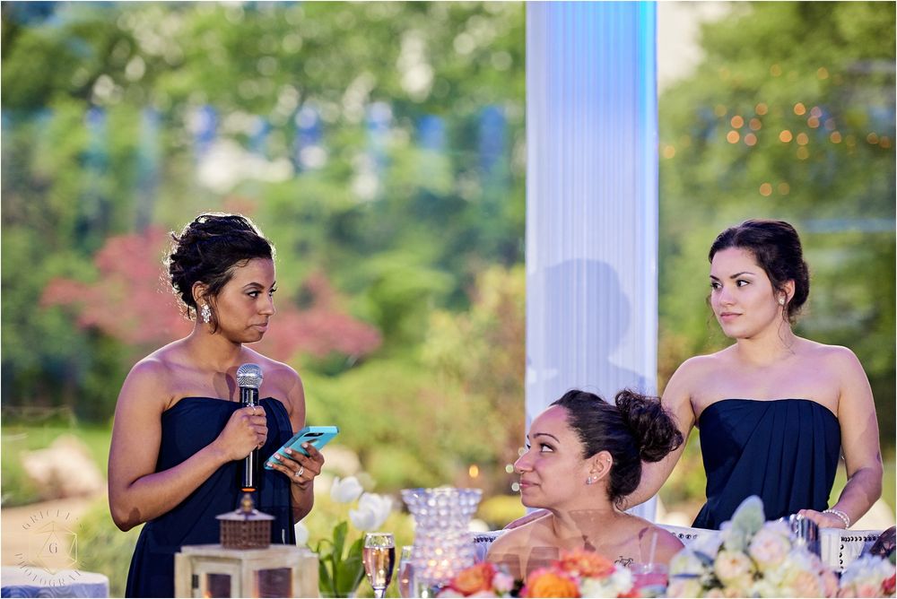 Wedding party members in navy dresses seated at an outdoor reception table.