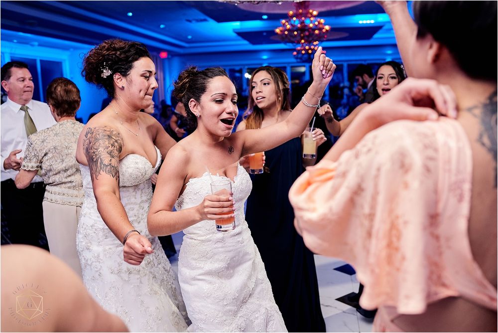 Wedding celebration with dancing guests in formal attire under dramatic blue lighting.