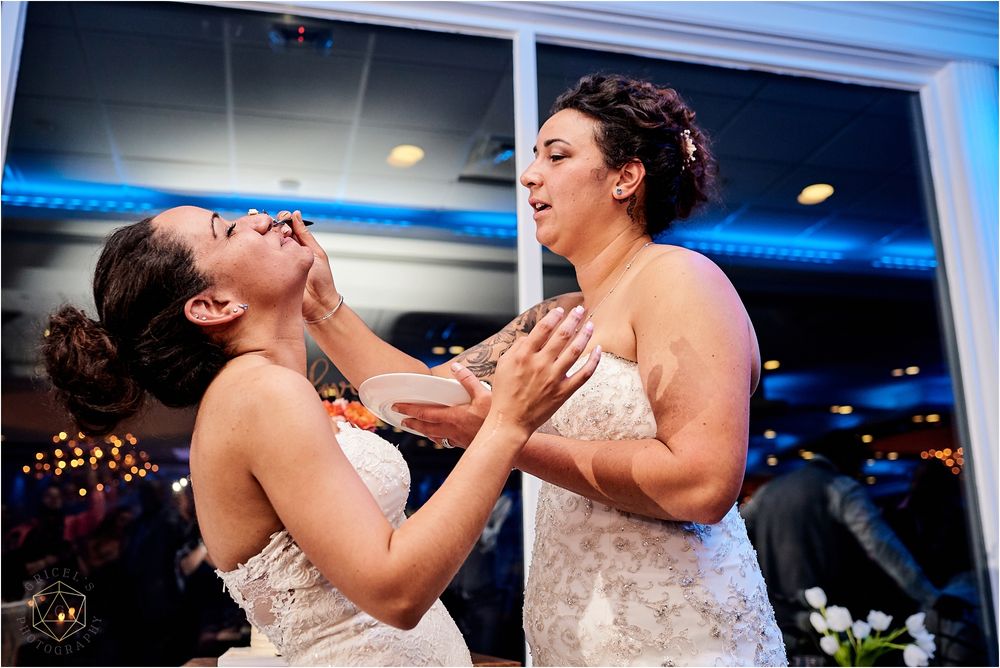 Two people in white dresses share a joyful moment during wedding reception.