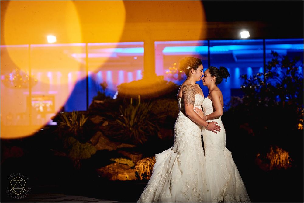 Romantic evening portrait of couple in white dresses with blue and orange lighting effects.