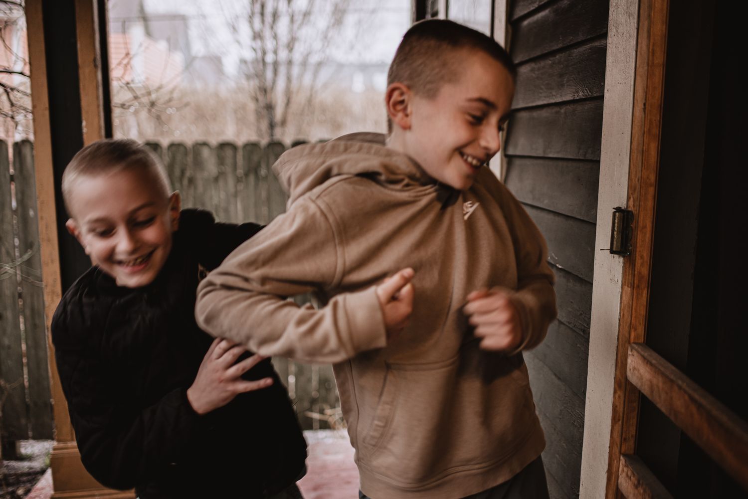 Two people sharing a playful moment on a covered porch in natural lighting.