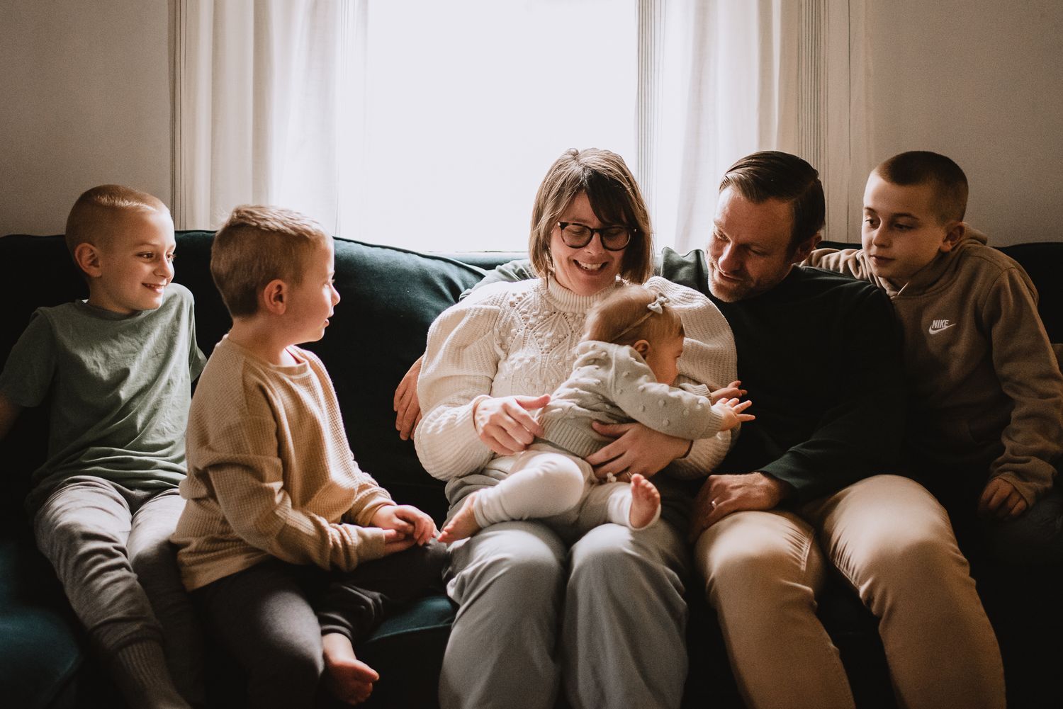 Tender family moment shared on a comfortable couch in natural window light.