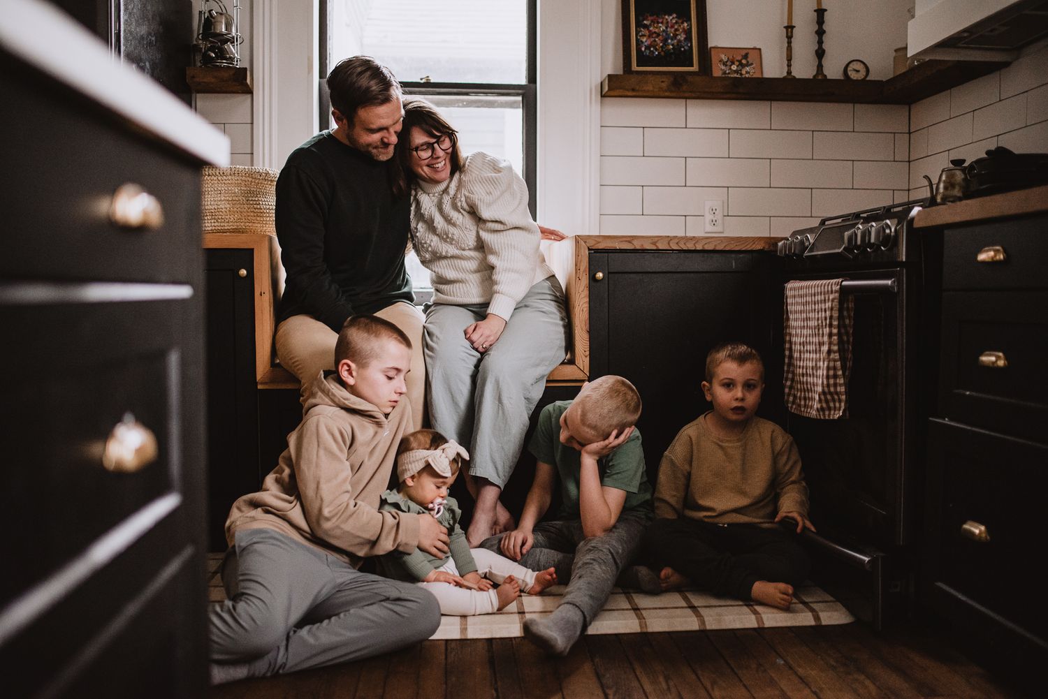 Casual gathering in a modern kitchen with white tile backsplash and dark cabinets.