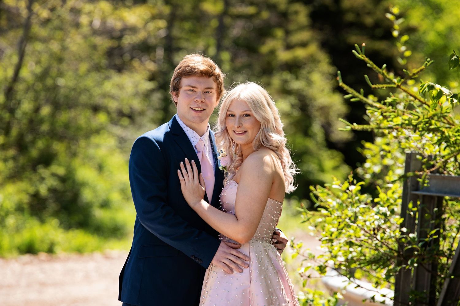 Outdoor engagement portrait of couple in formal attire surrounded by spring greenery.